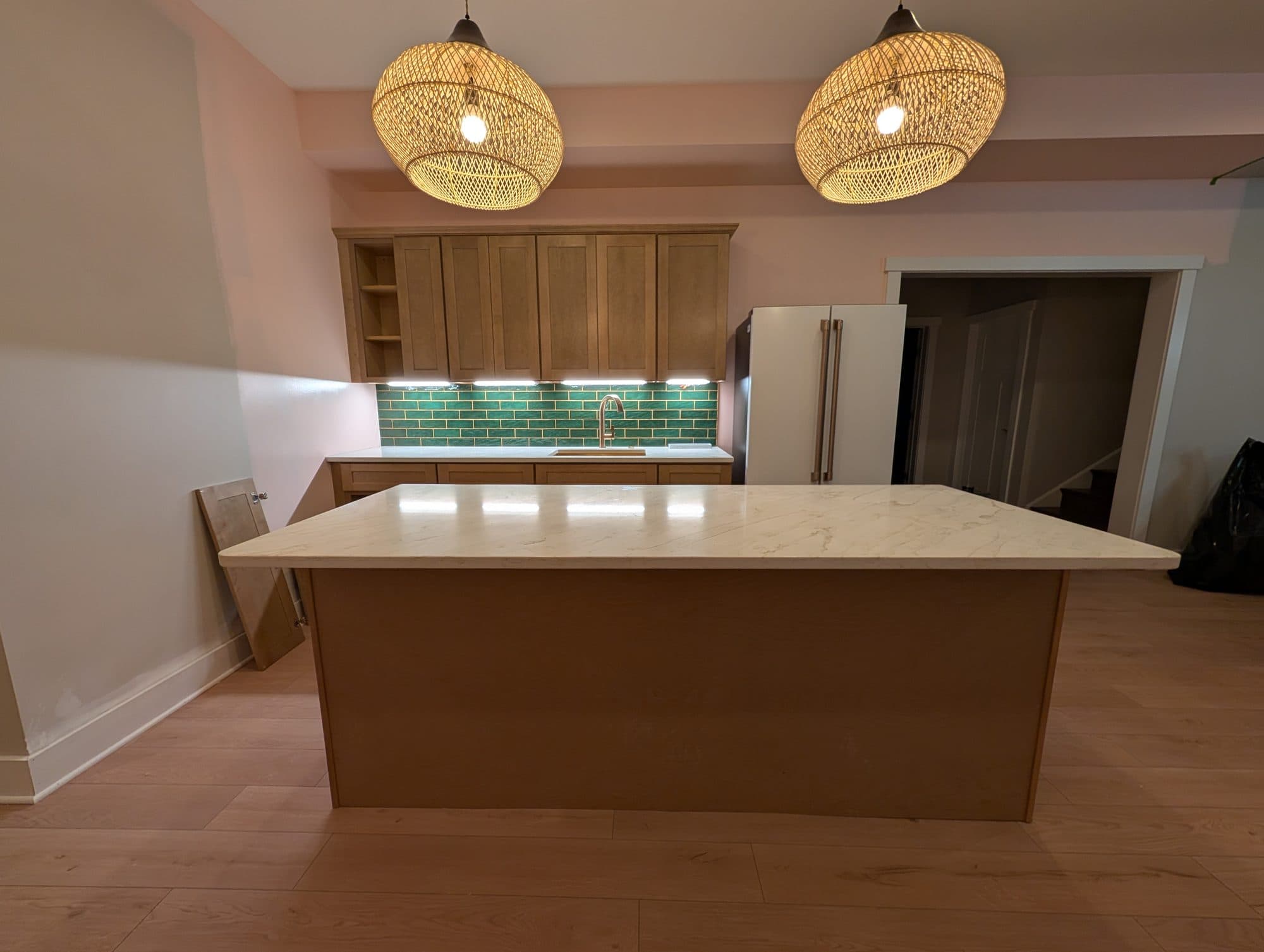 Finished basement wet bar, wide view showing the refrigerator and cabinetry